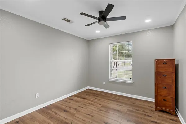 an empty room with wooden floor ceiling fan and windows