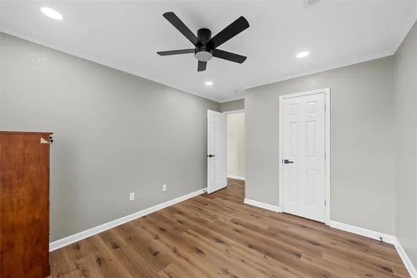 an empty room with wooden floor and ceiling fan