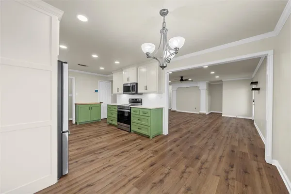 a open kitchen with stainless steel appliances granite countertop a refrigerator a oven a sink and a dining table with wooden floor