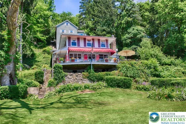 a view of a house with a big yard and large trees
