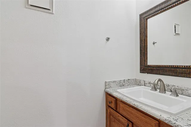 a bathroom with a granite countertop toilet a sink and a mirror
