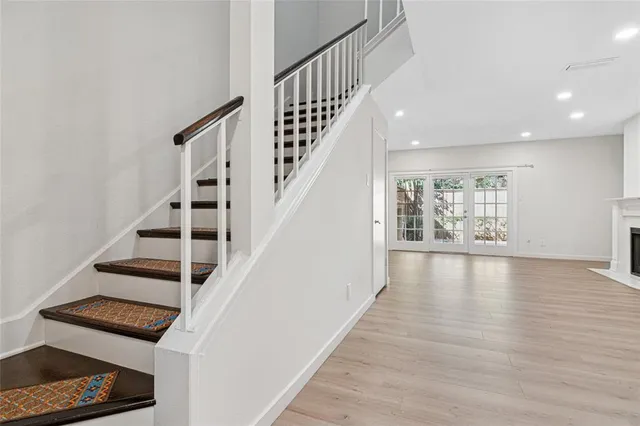a view of an empty room with wooden floor and staircase