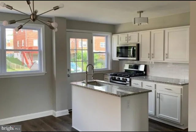 a kitchen with granite countertop a sink appliances cabinets and a window