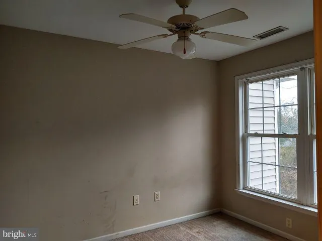 an empty room with a window and a fan