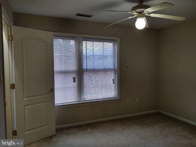 an empty room with windows and fan