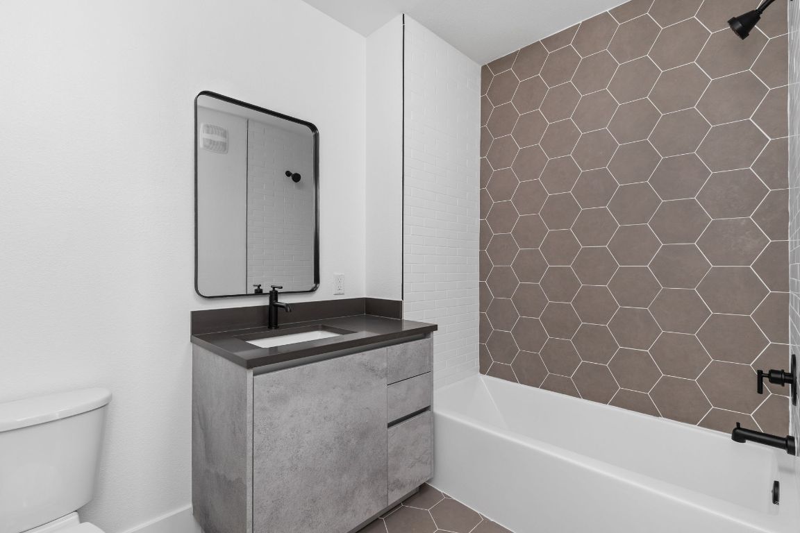 4315 South Congress Avenue, Unit 527 Austin, TX 78745 - Photo 19 of 37 a bathroom with a granite countertop sink a toilet and bathtub