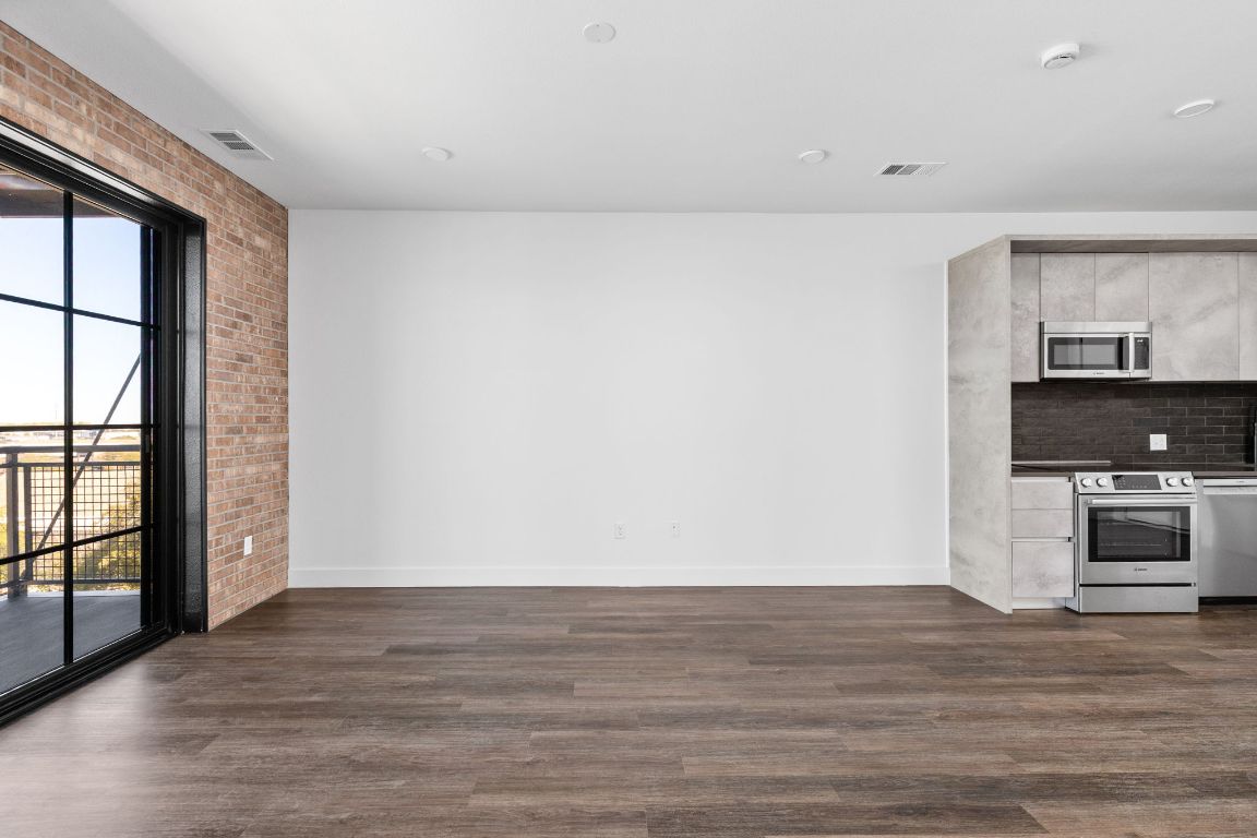 4315 South Congress Avenue, Unit 527 Austin, TX 78745 - Photo 3 of 37 a view of kitchen and empty room with wooden floor