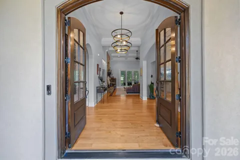 a view of a hallway with wooden floor and a chandelier
