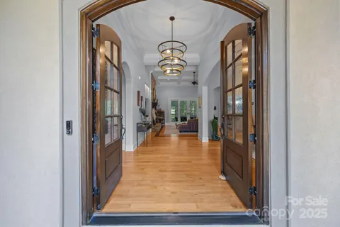 a view of a hallway with wooden floor and a chandelier