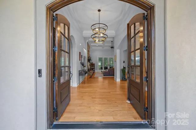 a view of a hallway with wooden floor and a chandelier