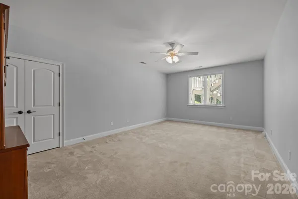 an empty room with windows and ceiling fan