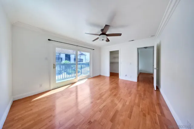 a view of empty room with wooden floor and fan