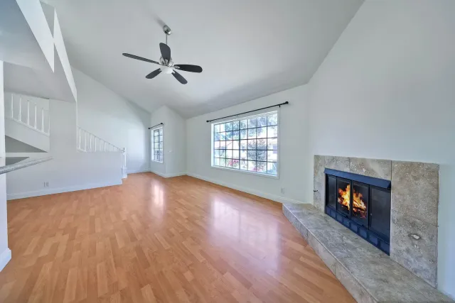 an empty room with wooden floor fireplace and windows