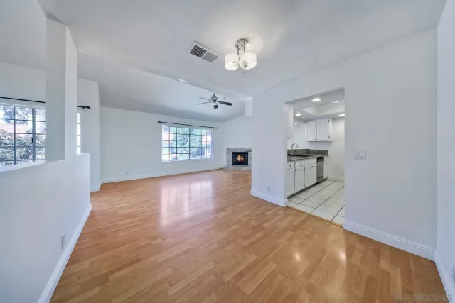 a view of empty room with kitchen natural and wooden floor