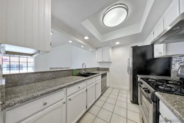 a kitchen with granite countertop a sink a counter space appliances and cabinets