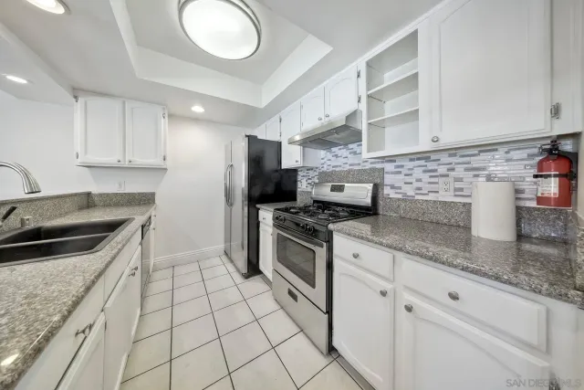 a kitchen with granite countertop a sink a stove top oven and cabinets