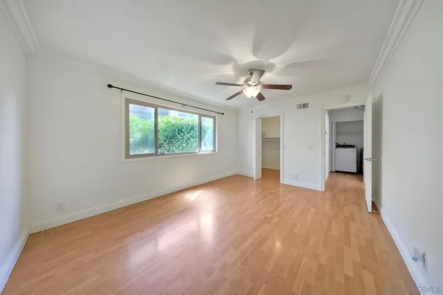 a view of an empty room with a window and wooden floor