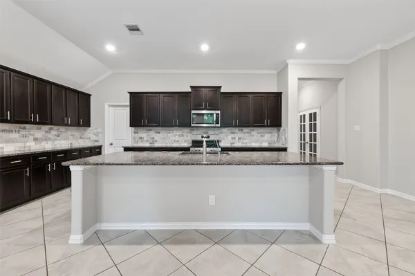 a large kitchen with granite countertop a cabinets and a stove top oven