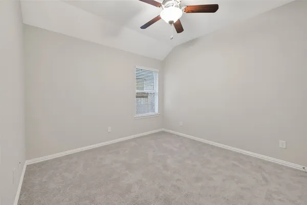 an empty room with a chandelier fan and windows