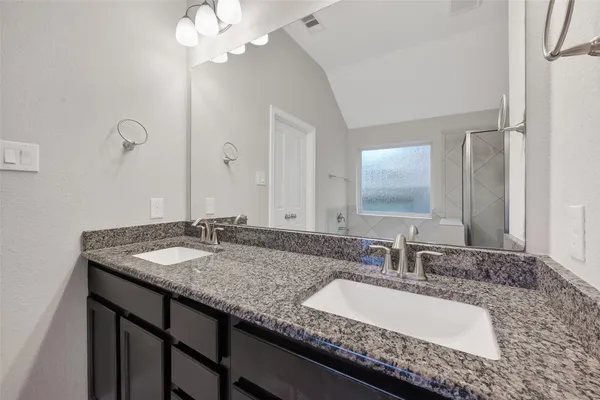 a bathroom with a granite countertop double vanity sinks and a mirror