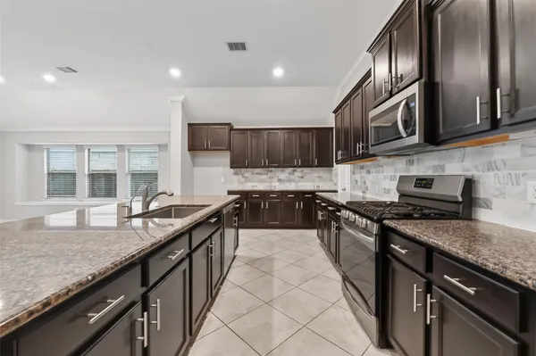 a kitchen with stainless steel appliances granite countertop a stove a sink dishwasher a refrigerator and a microwave