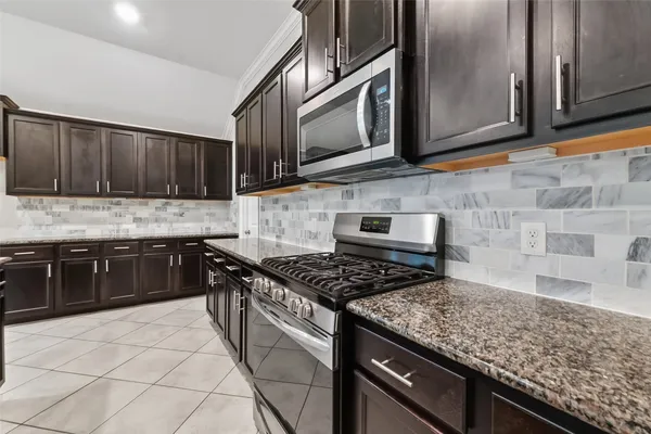 a kitchen with stainless steel appliances granite countertop a stove a sink and a microwave