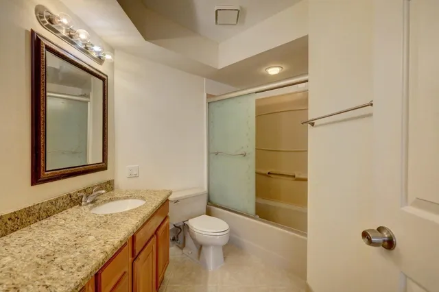 a bathroom with a granite countertop sink toilet and shower