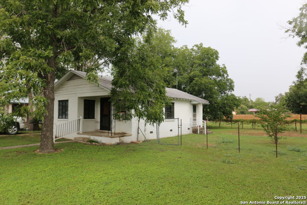 705 Florence Street Castroville, TX 78009 - Photo 1 of 1 a front view of house with a garden and trees