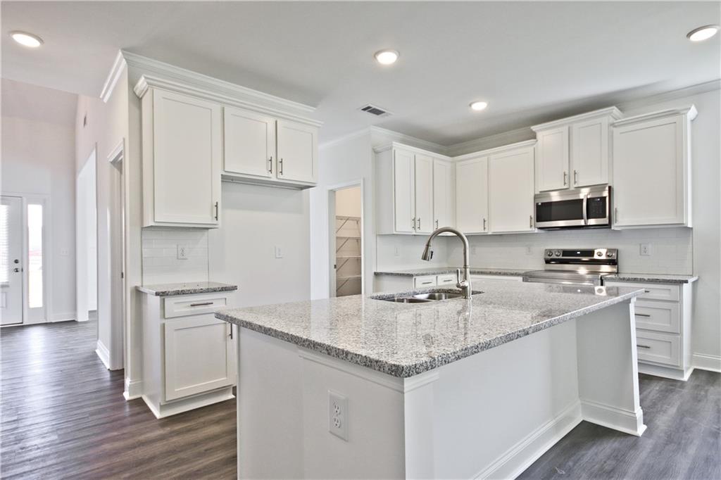 5985 Spring Way Lithonia, GA 30058 - Photo 12 of 34 a kitchen with kitchen island granite countertop white cabinets and sink