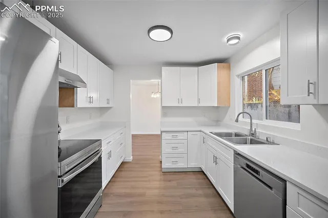 a kitchen with a sink dishwasher a stove and white cabinets