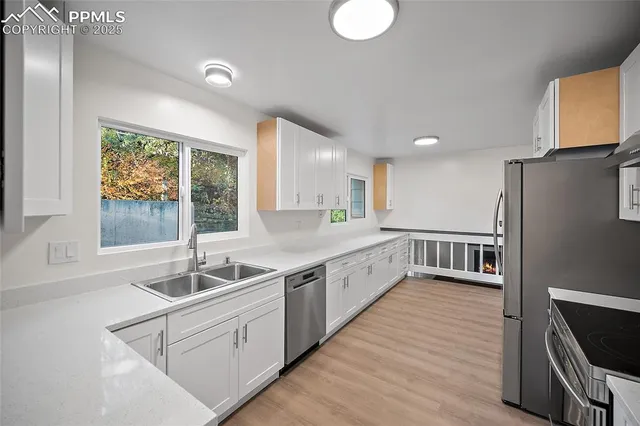 a large white kitchen with a sink and dishwasher a refrigerator with wooden floor