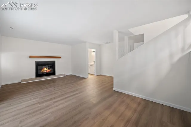 a view of an empty room with wooden floor and a fireplace