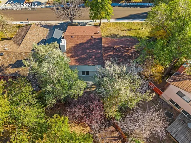an aerial view of a house with swimming pool and large trees