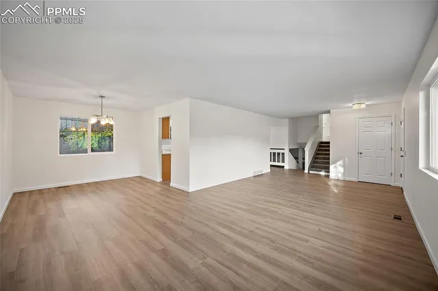 a view of empty room with wooden floor and window