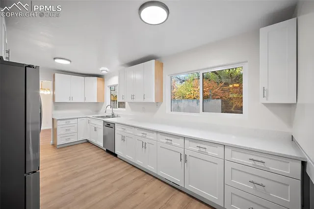 a kitchen with granite countertop white cabinets white appliances a sink and a large window