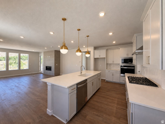 539 East Rimrock Lane Heber City, UT 84032 - Photo 1 of 13 Open-concept living space featuring wood-finish flooring, a contemporary fireplace with a tiled surround, and a kitchen island with pendant lighting. This image has been digitally staged or enhanced via artificial intelligence. These photos are for illust