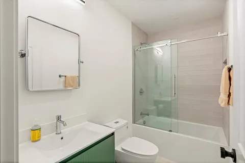 a view of a hallway with wooden floor and a bathroom