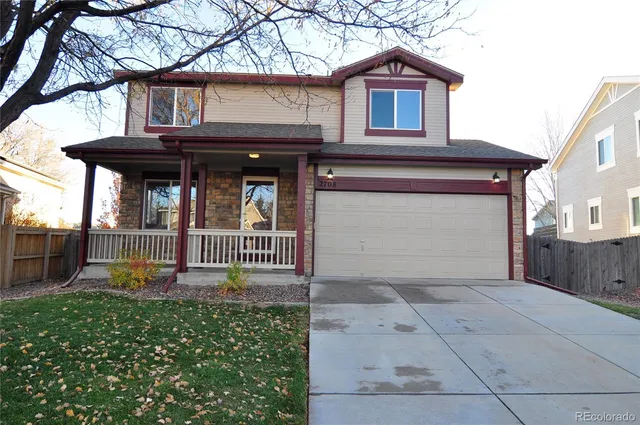 a view of a house with a small yard and a large tree