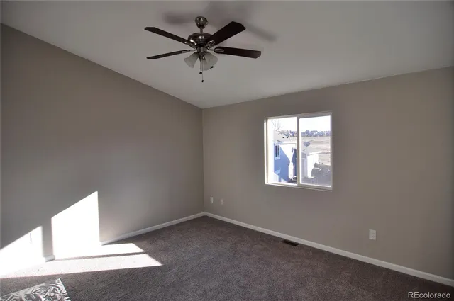 an empty room with a window and a fan