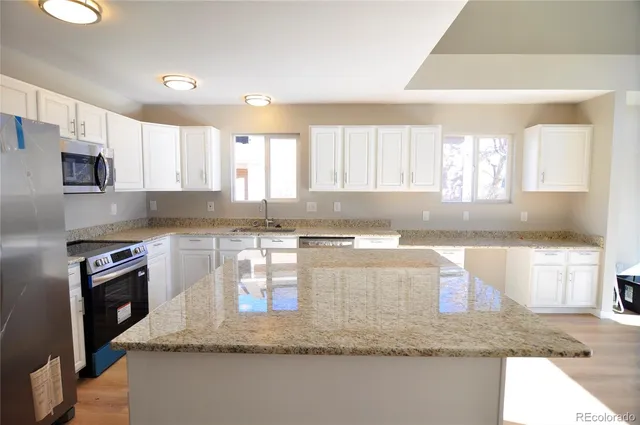 a kitchen with granite countertop a sink a window stainless steel appliances and a counter top space