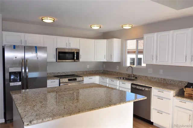 a kitchen with stainless steel appliances granite countertop a sink a stove and a granite counter tops