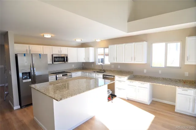 a large kitchen with granite countertop a sink and a stove top oven with wooden floor