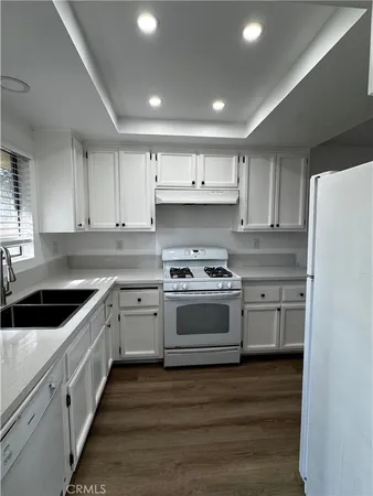 a kitchen with granite countertop white cabinets and white appliances