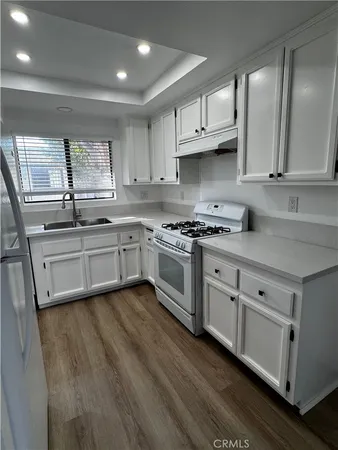 a kitchen with stainless steel appliances granite countertop a stove a sink and white cabinets