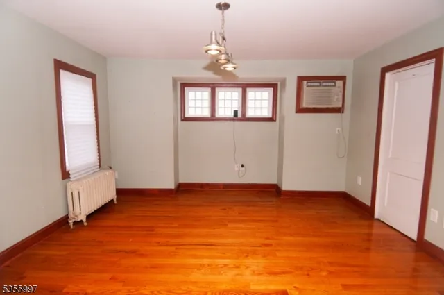 a view of an empty room with window and wooden floor