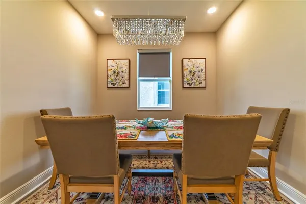 a large kitchen with granite countertop a dining table chairs stainless steel appliances and cabinets