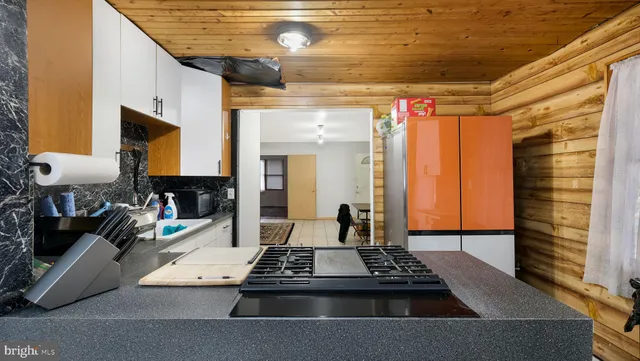 a living room with a black white checkered floor with a gaming machine and dining chairs