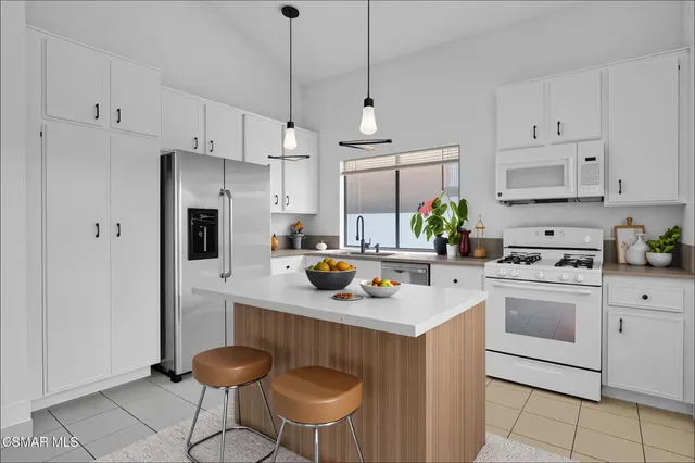 a kitchen with stainless steel appliances granite countertop a sink a stove a refrigerator and white cabinets