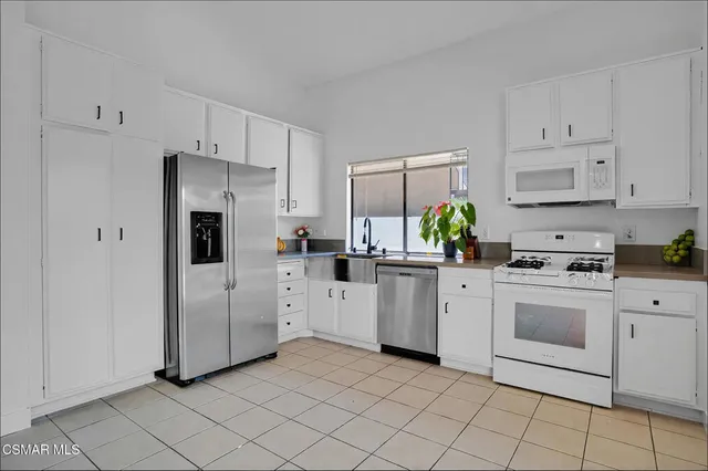 a kitchen with white cabinets stainless steel appliances and a sink