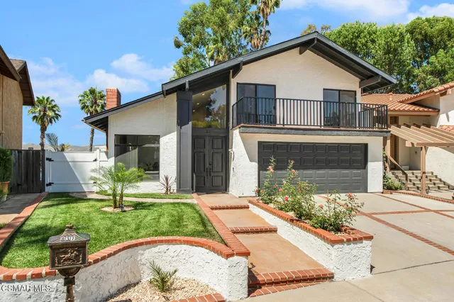 a front view of a house with a yard and potted plants